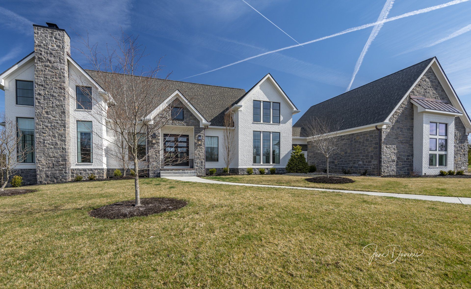 A large house with a lot of windows is sitting on top of a lush green lawn.
