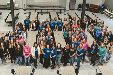 A large group of people are posing for a picture in a large room.