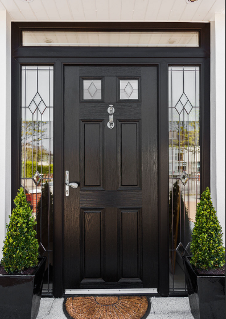 Black front door with glass side panels, silver hardware, and potted evergreens at the entrance