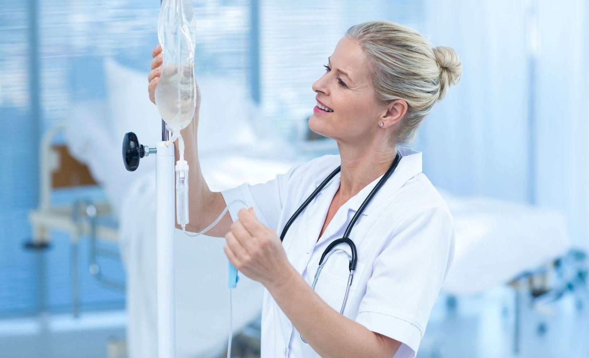 A female doctor is adjusting an iv in a hospital room.