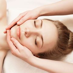 A woman is getting a massage on her face with her eyes closed