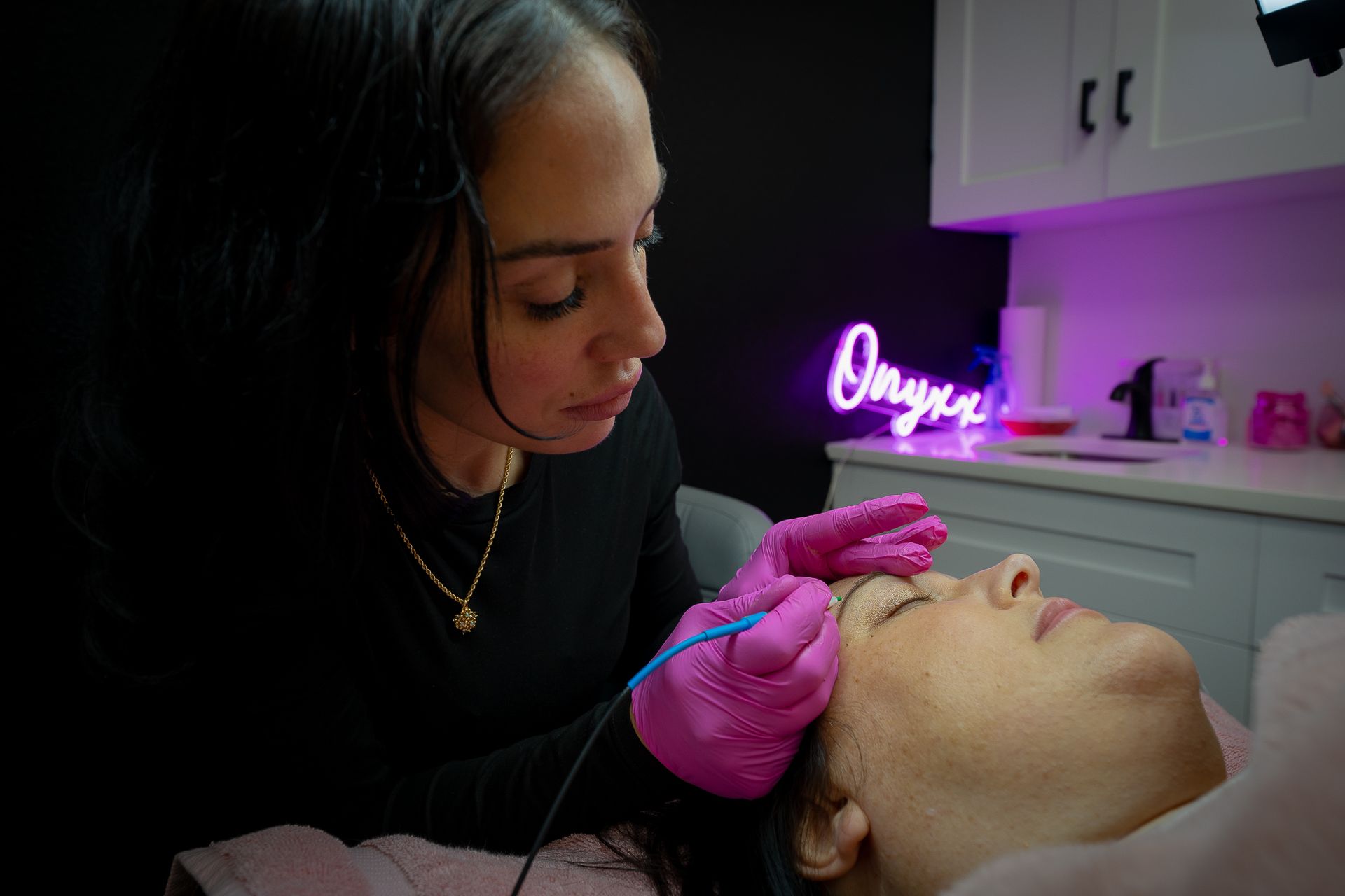 A woman is getting a tattoo on a woman's eyebrows in a salon.