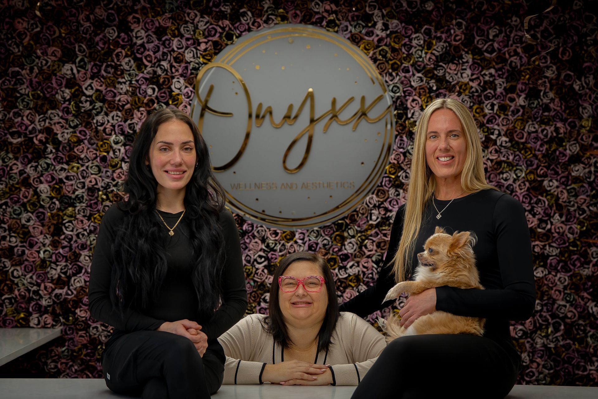 Three women are sitting on a table with a dog.