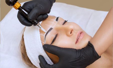 A woman is getting a tattoo of her eyebrows.