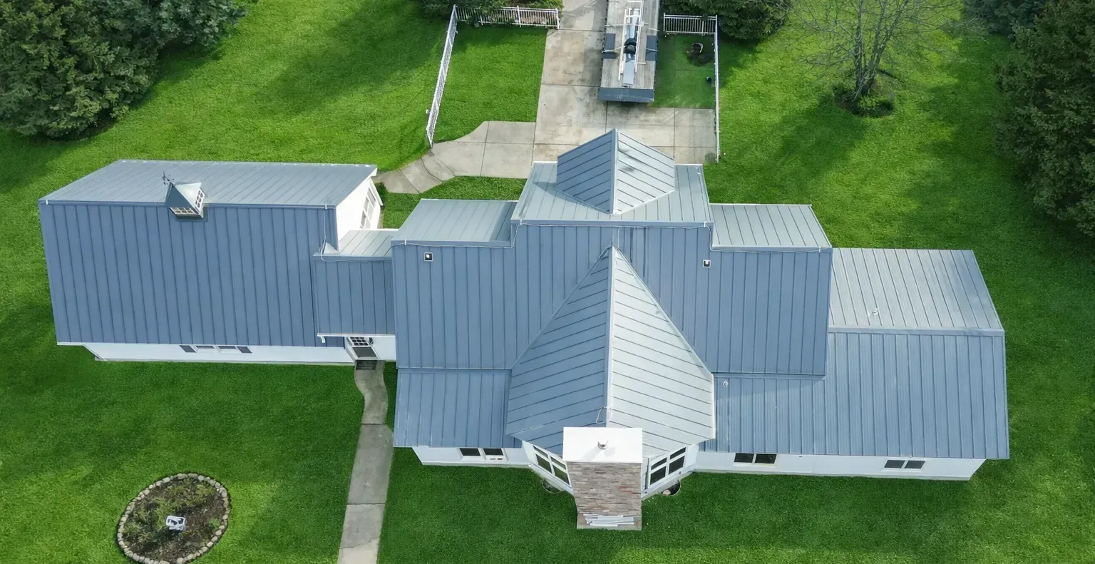 Aerial view of a white-roofed building with multiple wings on a grassy property.