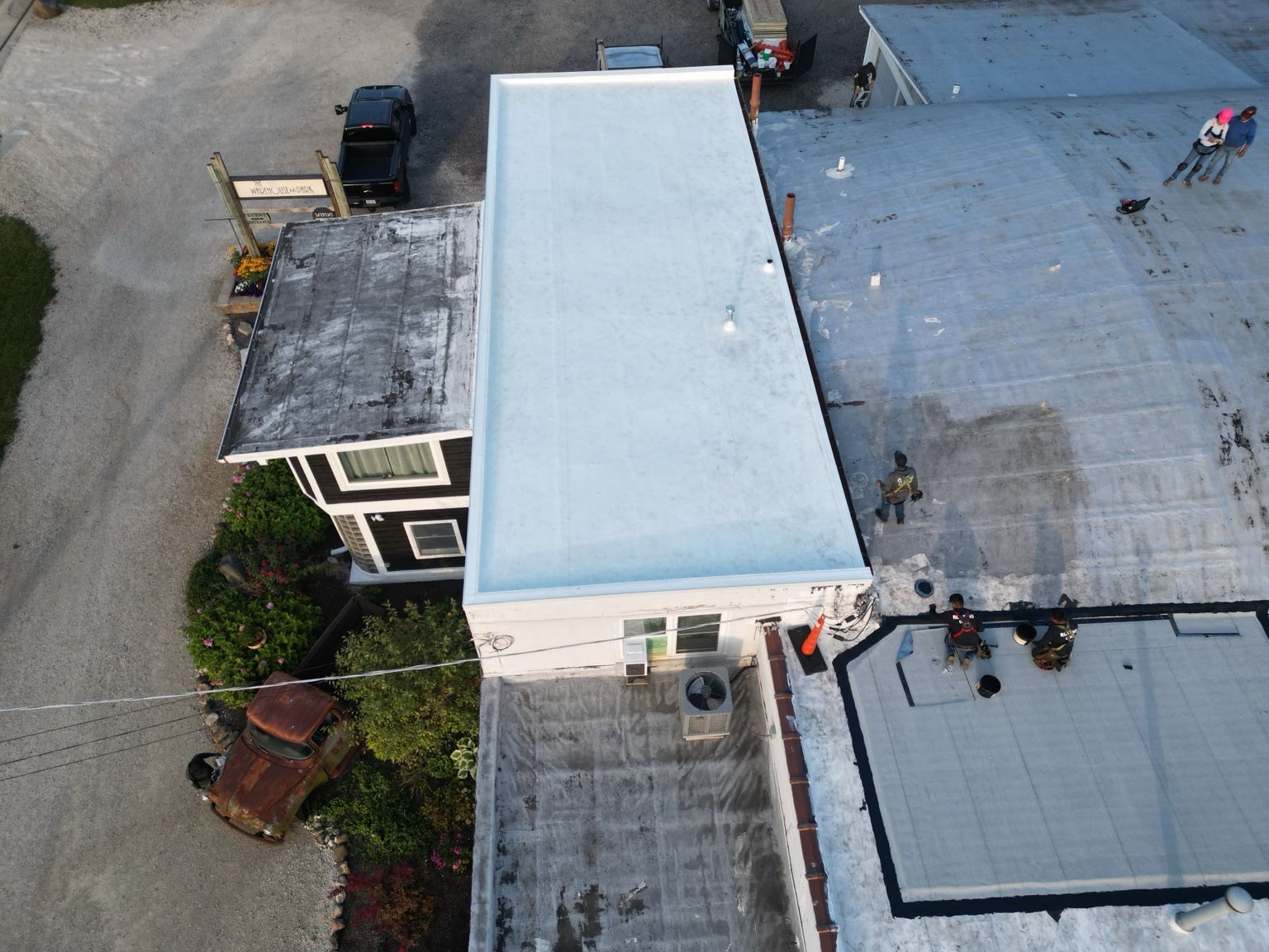Aerial view of a flat-roofed building with a large white rooftop section and nearby rooftop equipment.