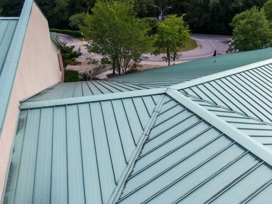 Light green metal rooftop overlooking trees and a road below
