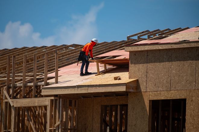 Construction worker installing roof on a house under construction