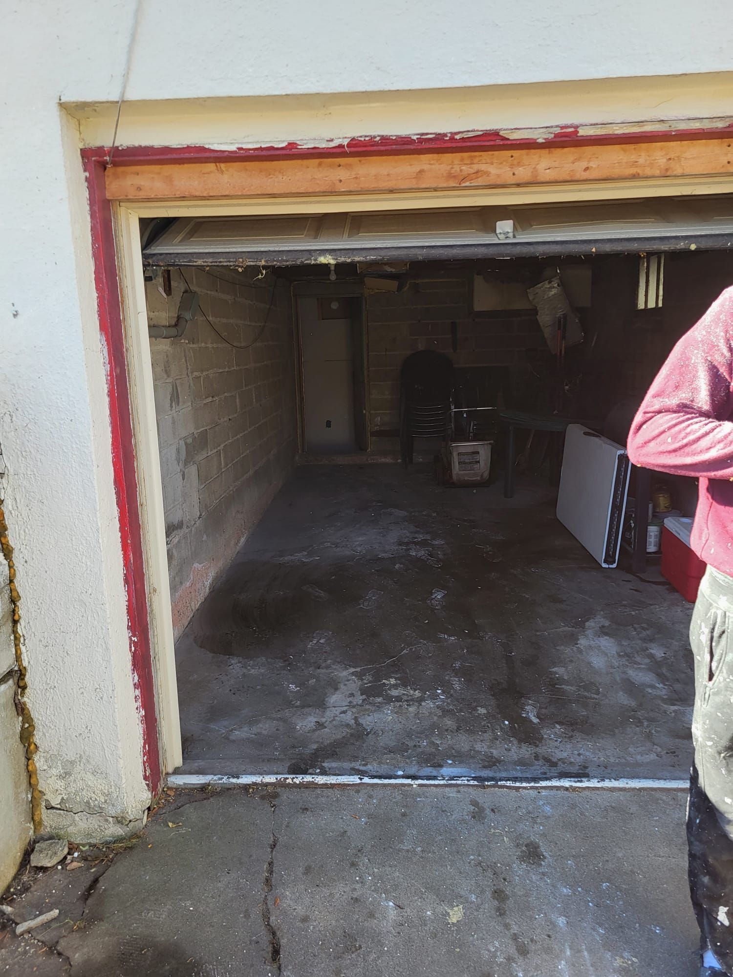 Open garage with concrete floor and interior, showing a person on the right.