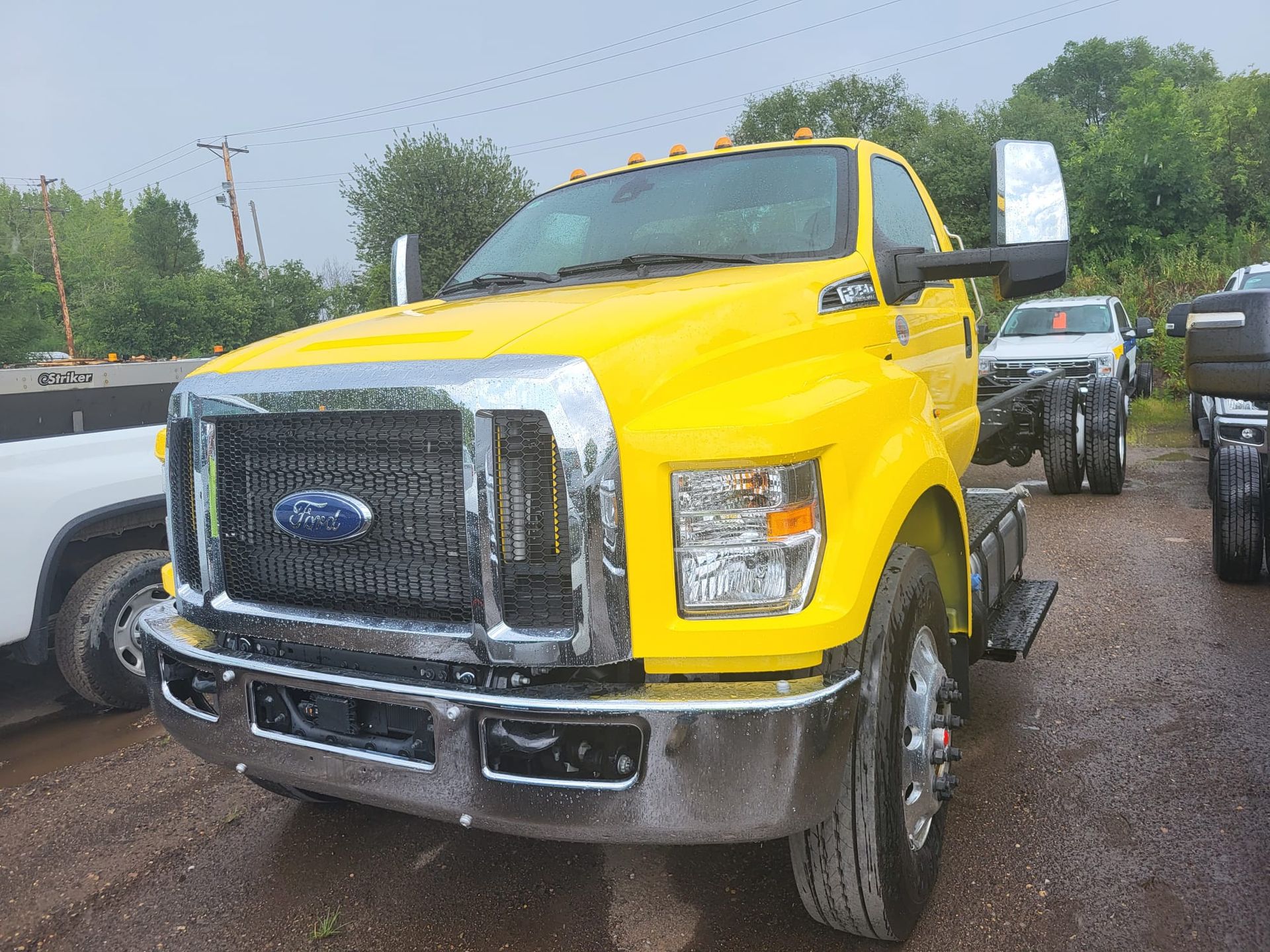Yellow Ford F-650 truck with chrome grill parked outdoors on an overcast day.
