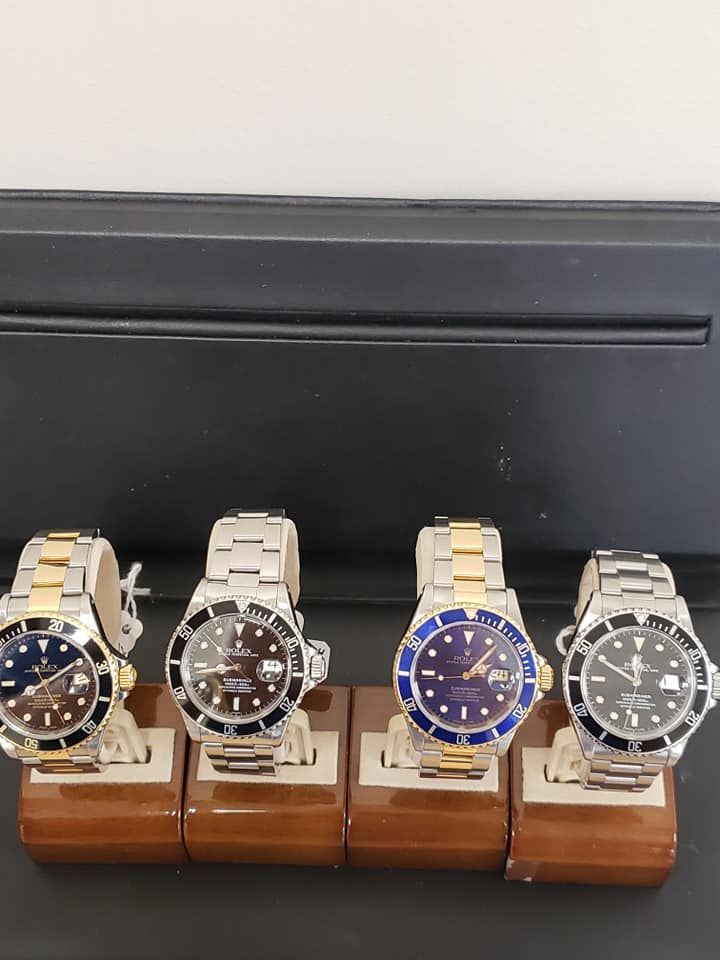 Four watches are lined up on wooden display stands