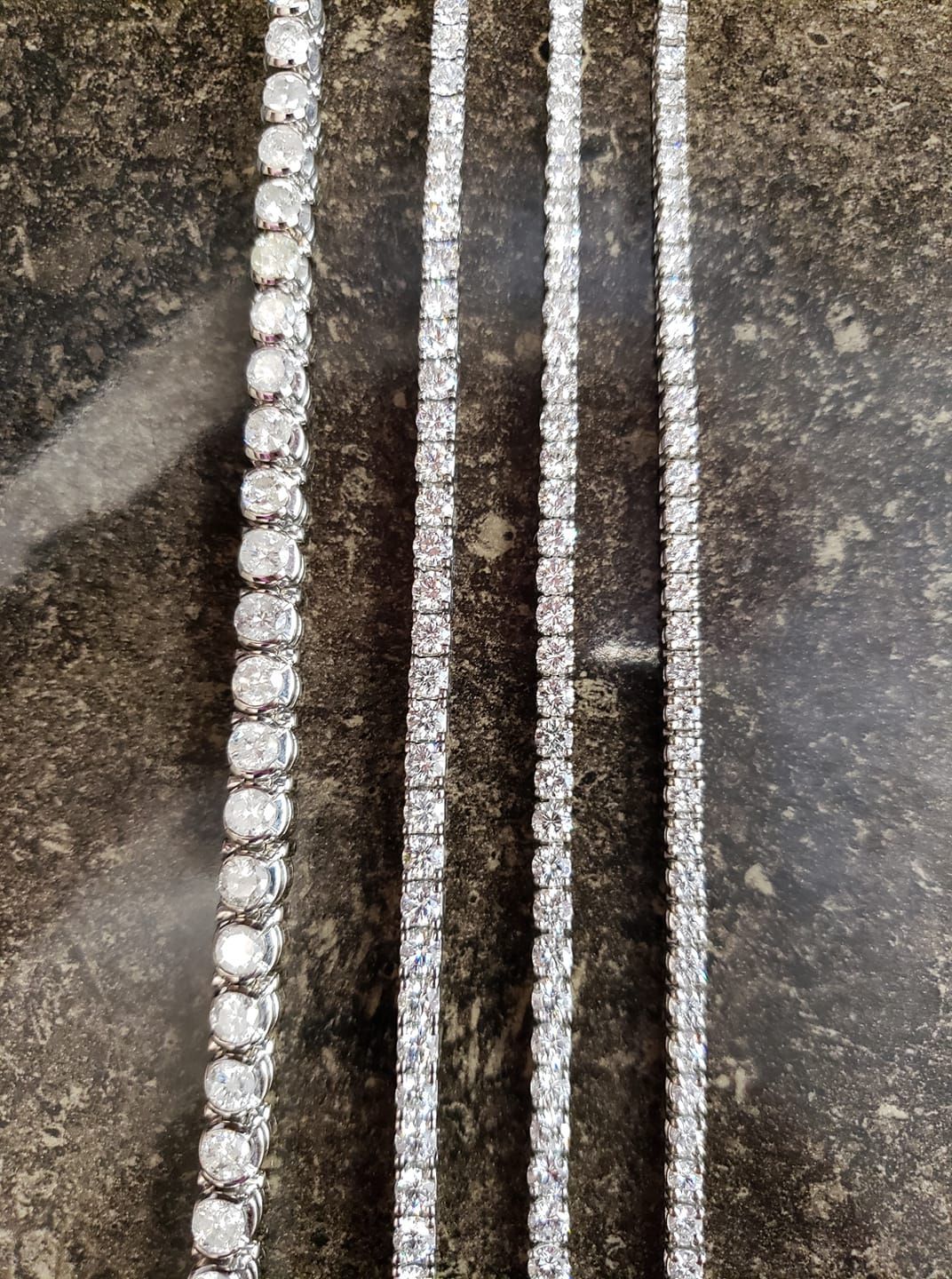 Three tennis chains are sitting on a marble surface.