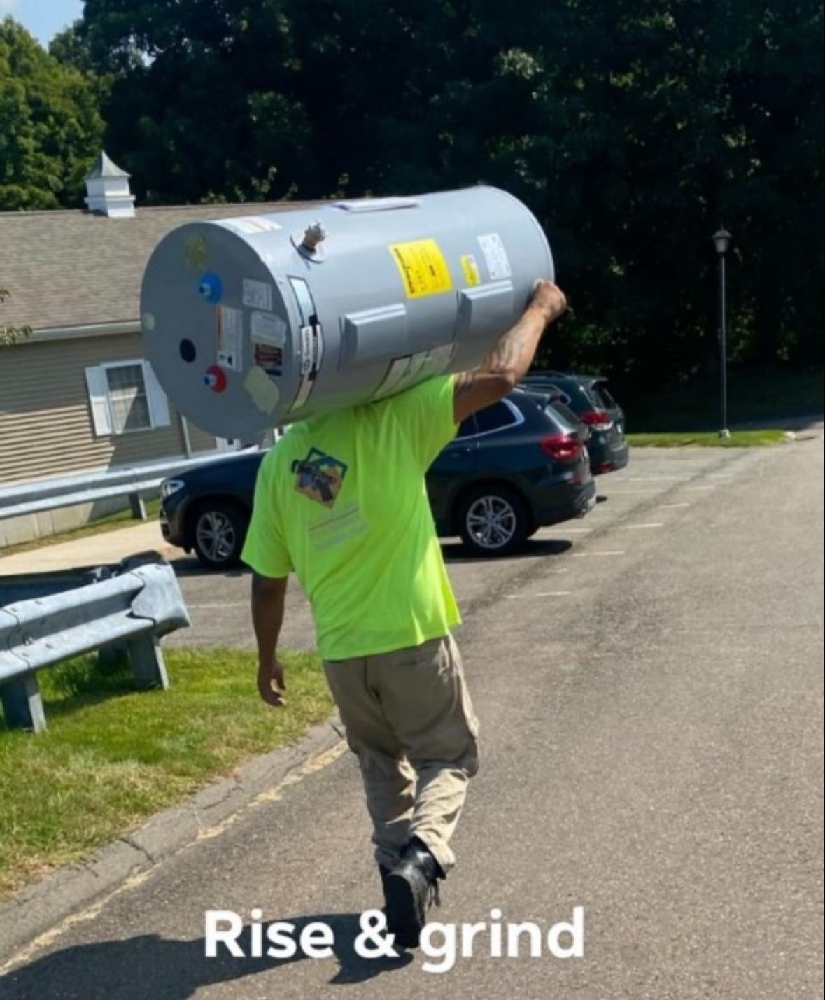 A man is carrying a large water heater on his shoulders