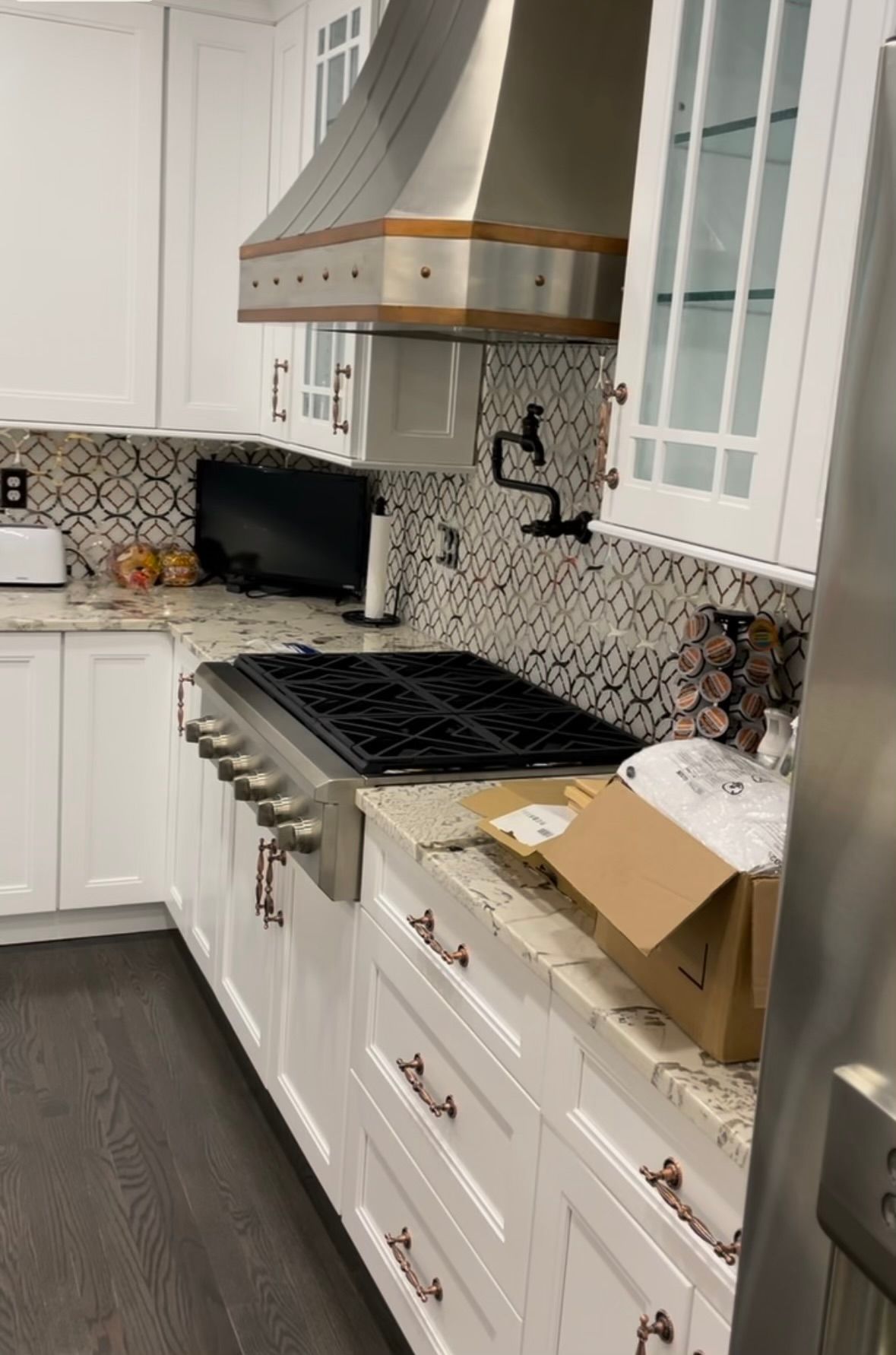A kitchen with white cabinets , stainless steel appliances , a stove and a refrigerator.