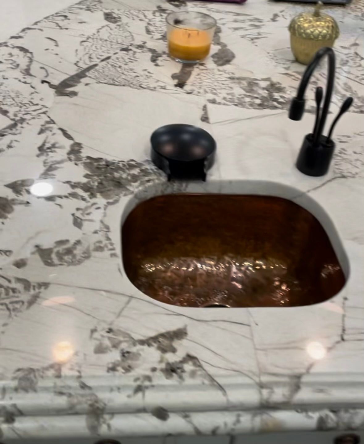 A copper sink sits on a white counter top