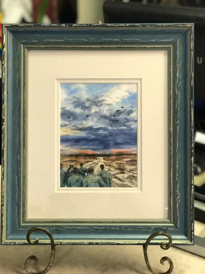 A painting in a blue frame is sitting on a metal stand.