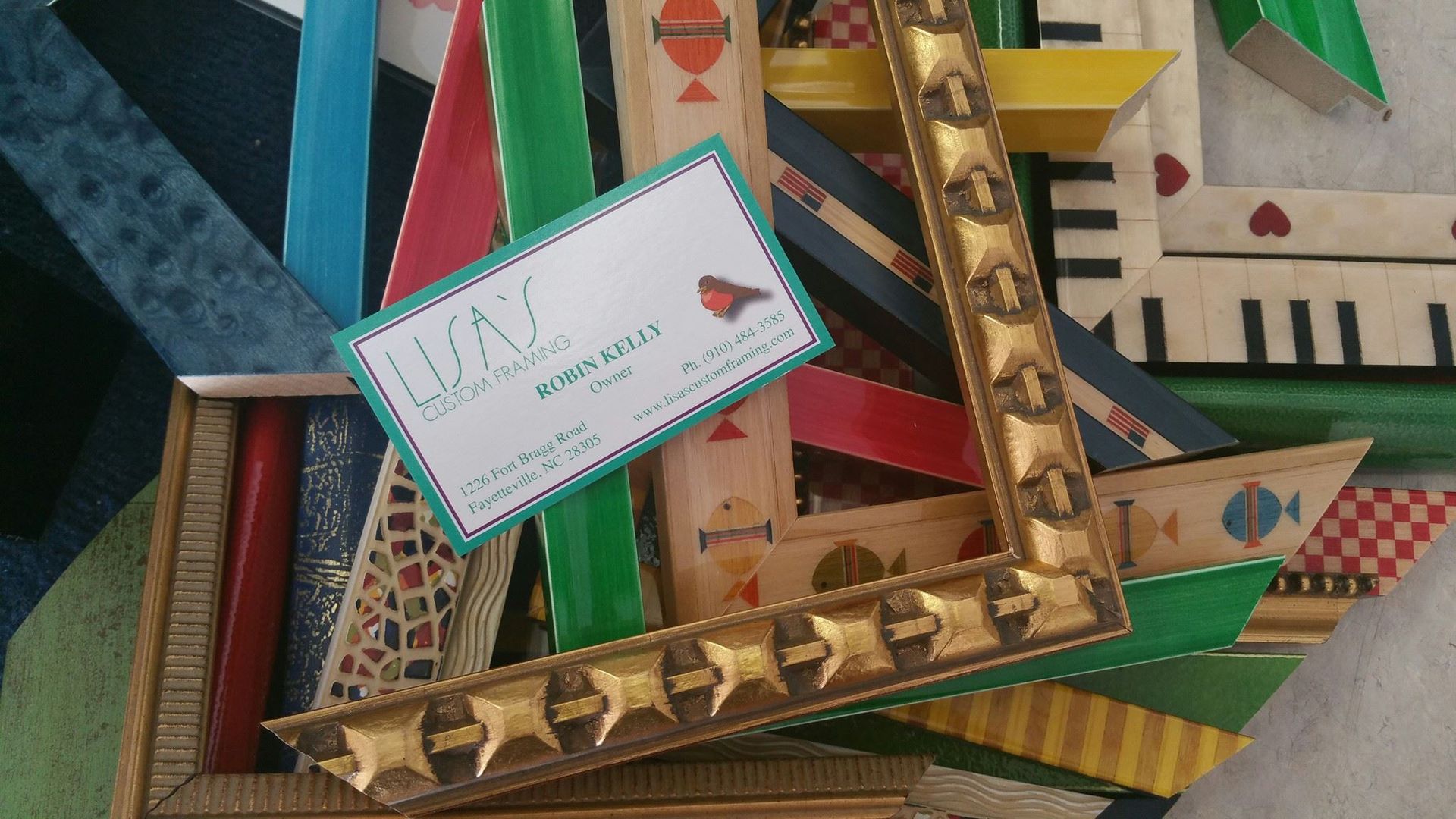 A business card is sitting on top of a pile of frames