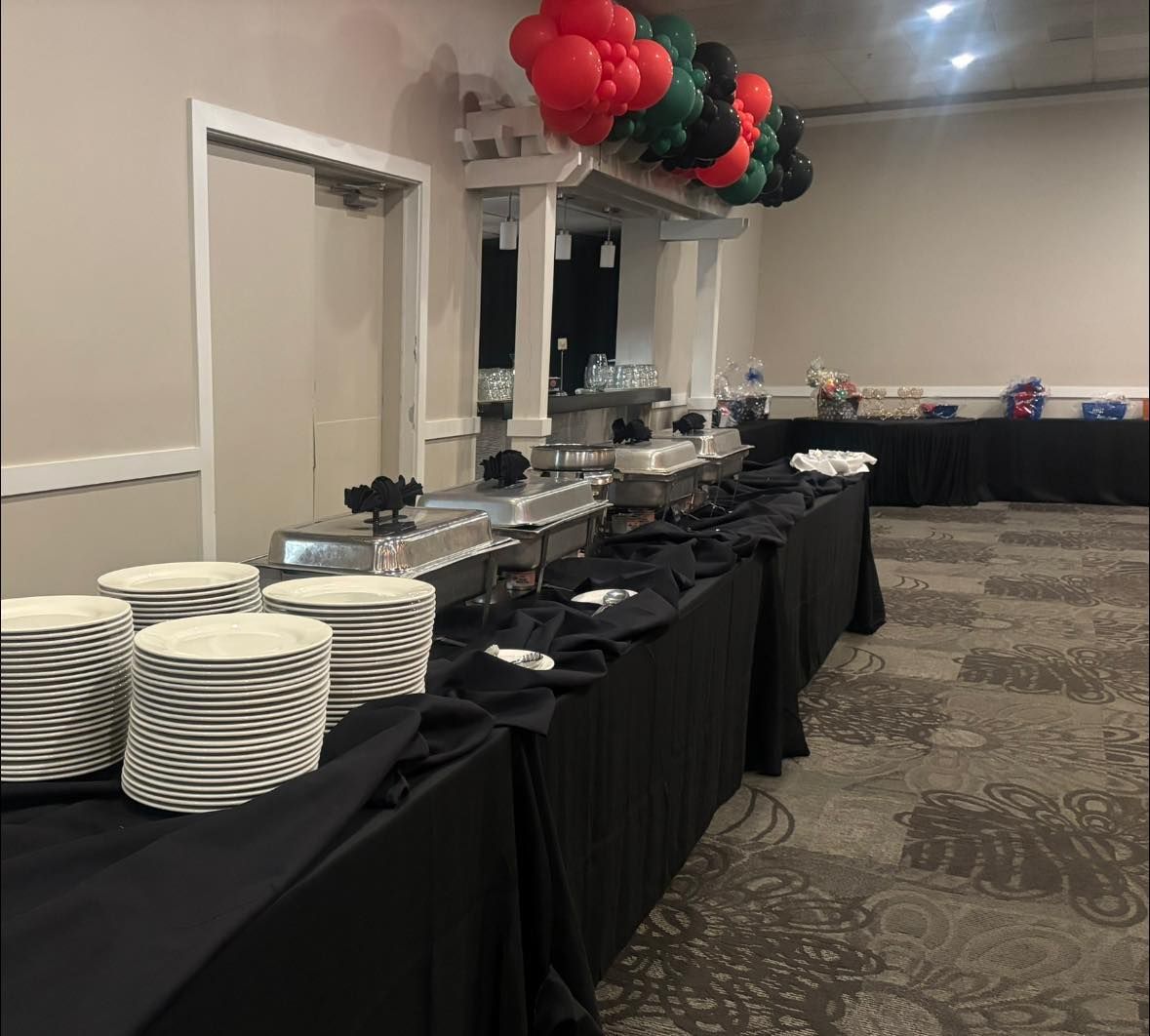 A buffet line with plates and balloons hanging from the ceiling