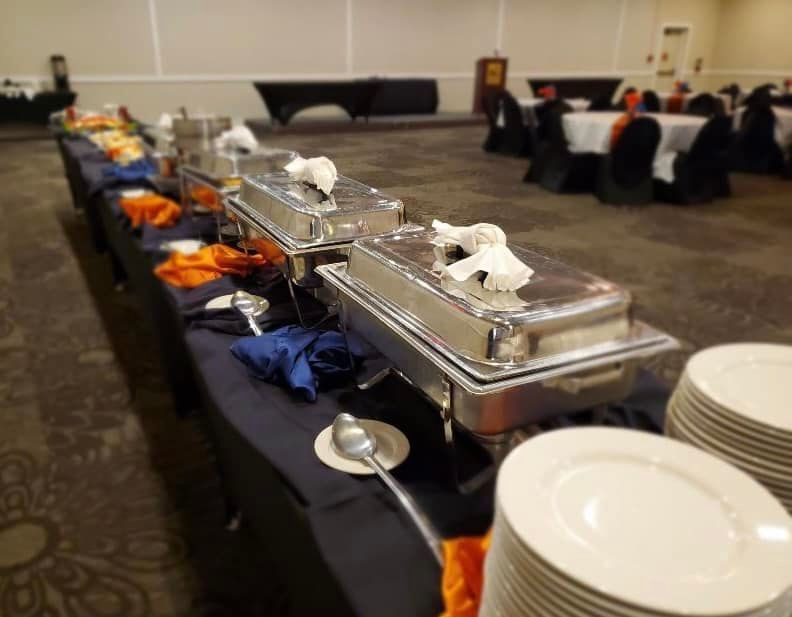 A long buffet table with plates and utensils on it