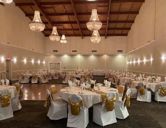 A large room with tables and chairs set up for a wedding reception.