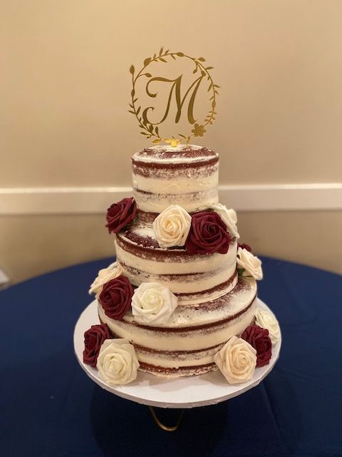 Three-tiered red velvet cake with floral accents, a gold 