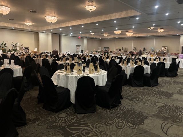 Large banquet hall set for an event with round tables covered in white and black chairs.
