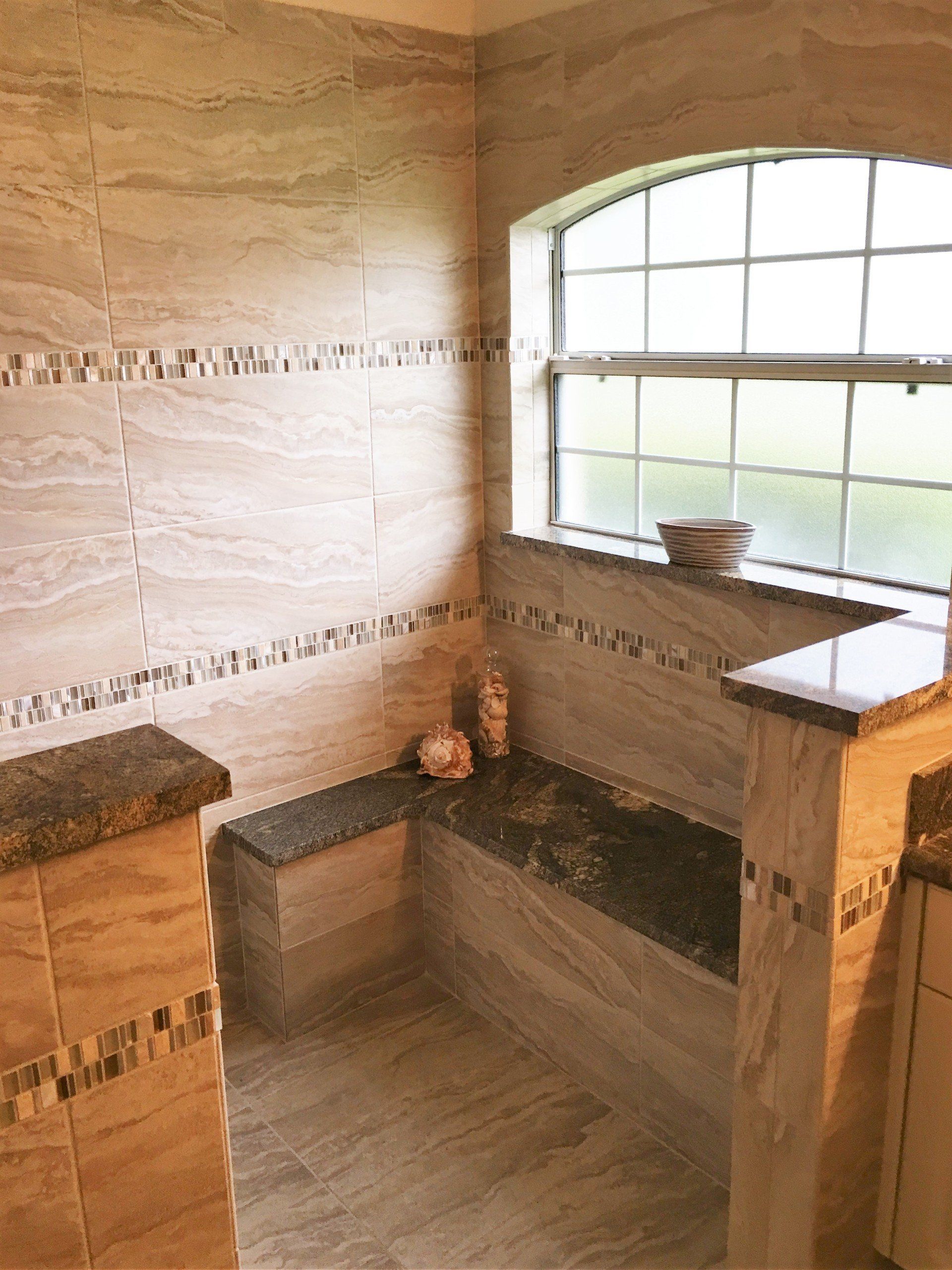 A bathroom with a window and a bench in it.