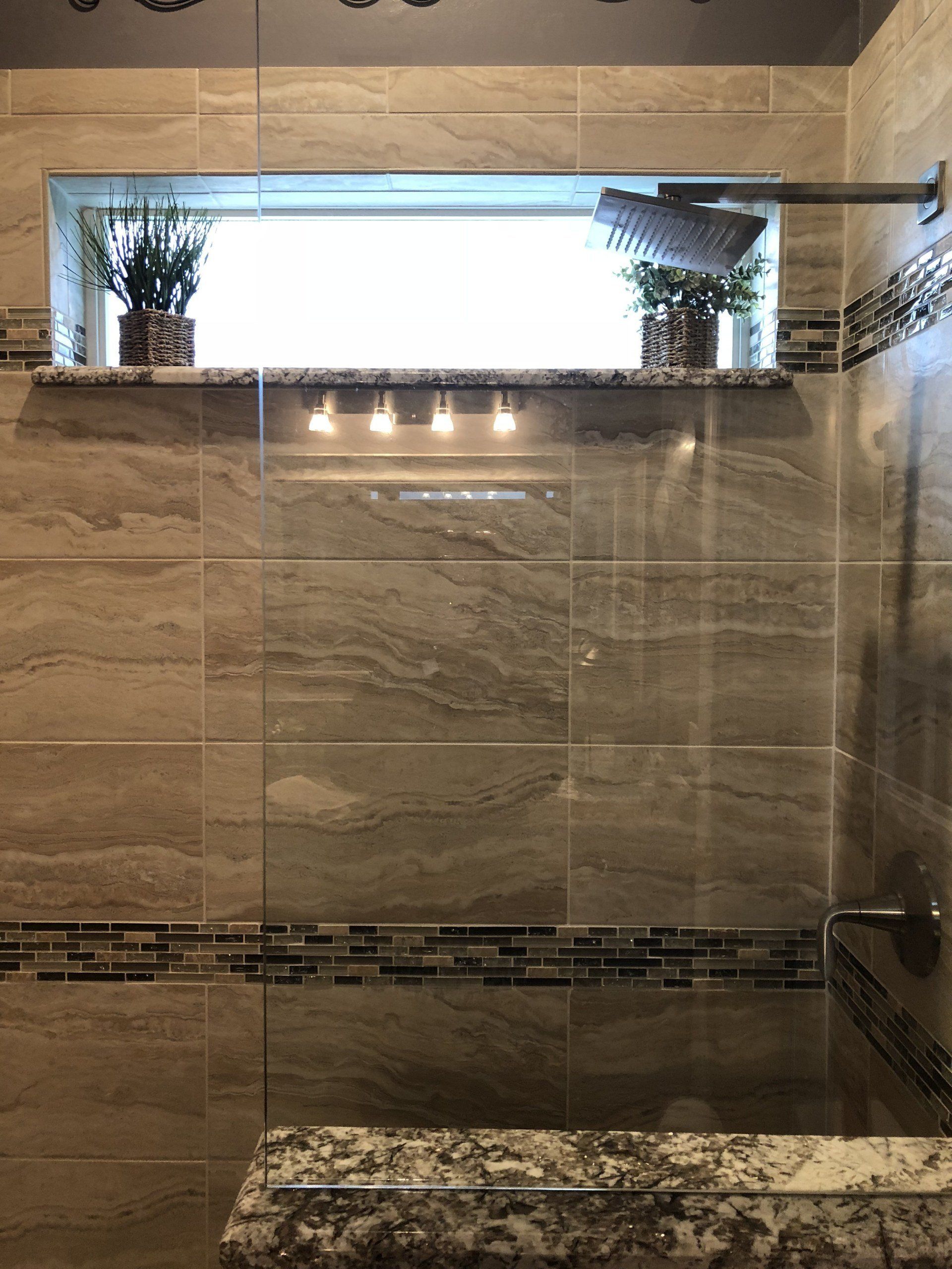 A bathroom with a walk in shower and a window.