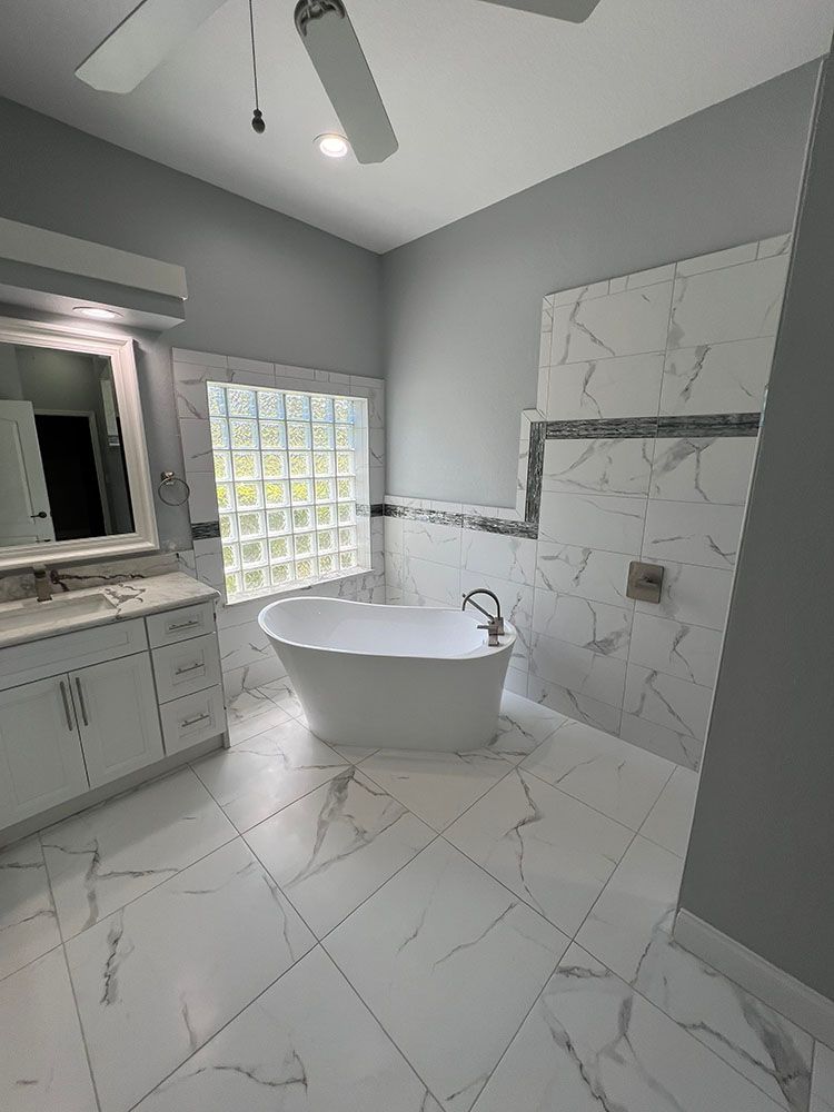 A bathroom with a tub, sink, mirror and ceiling fan