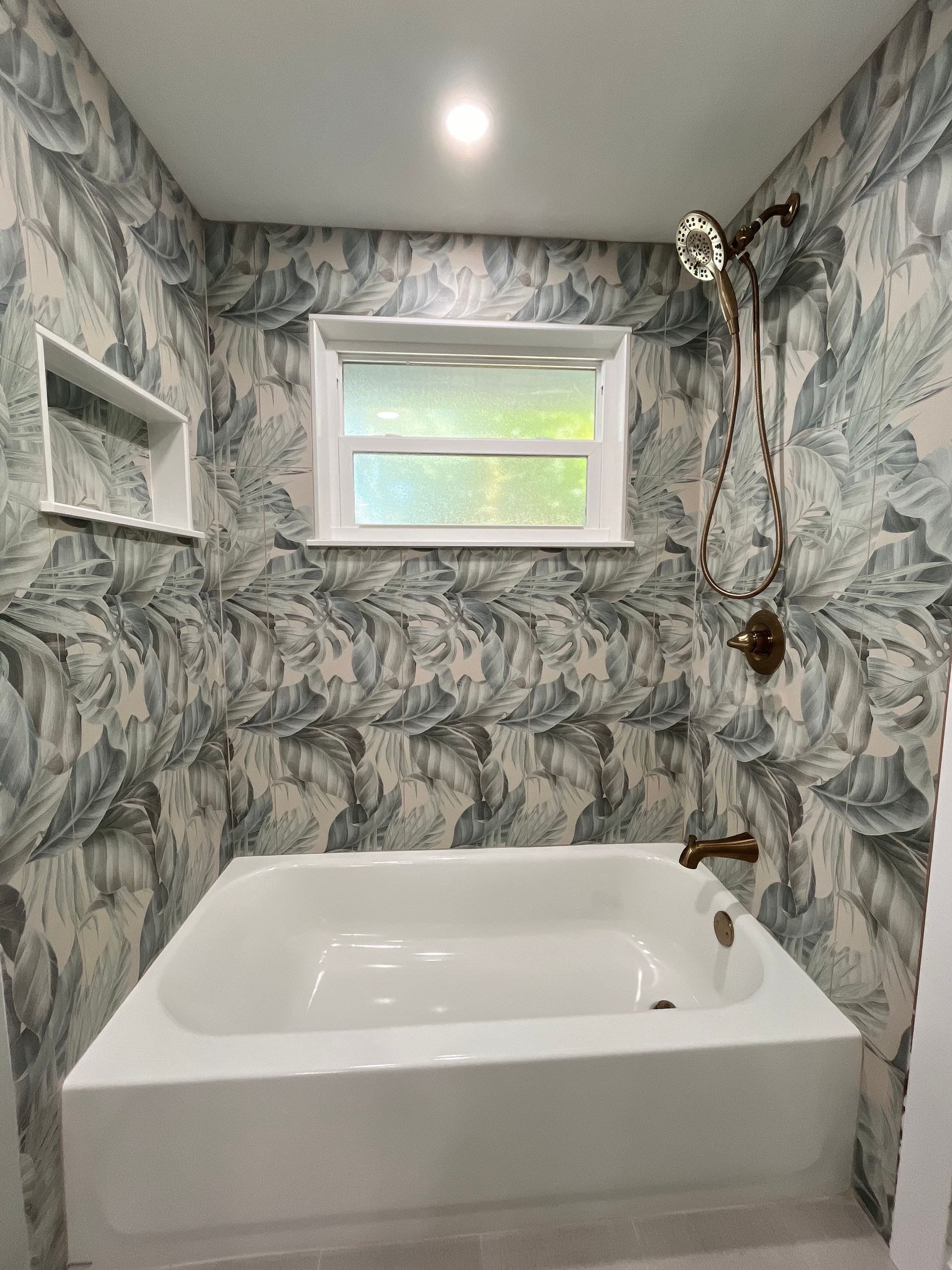 A bathroom with a bathtub, shower, and window.