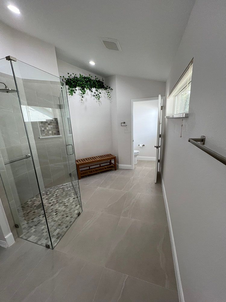 A bathroom with a walk in shower and a bench