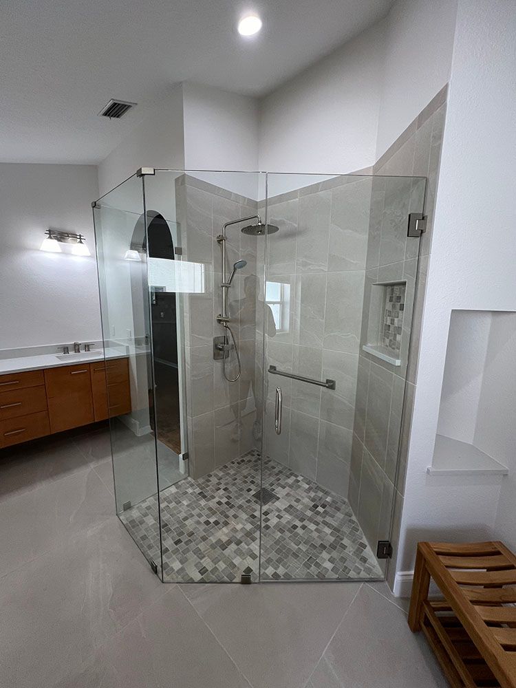 A bathroom with a walk in shower with a glass door