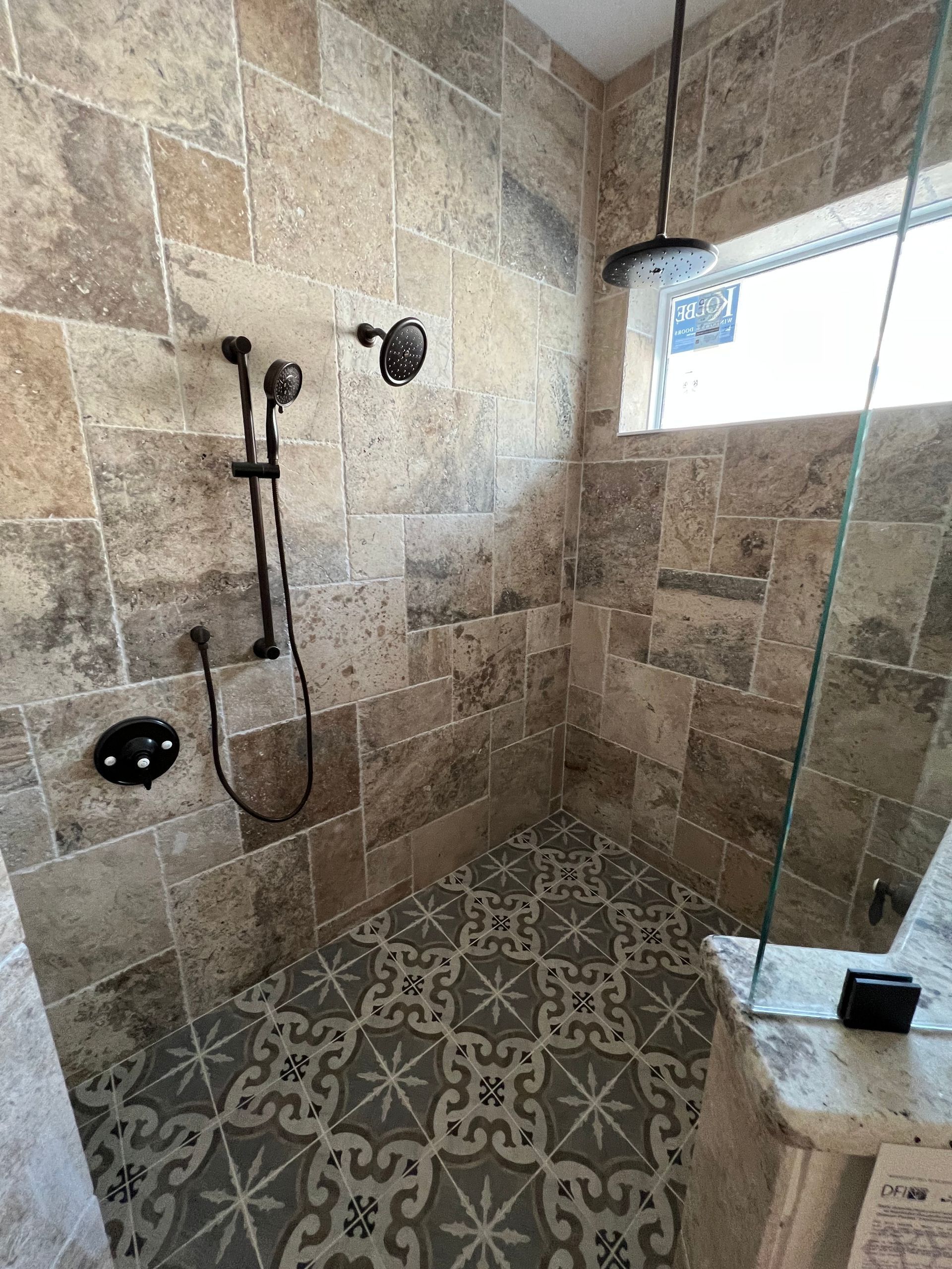 A bathroom with a walk in shower and a window.