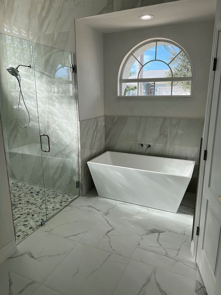 A bathroom with a tub, shower, and window
