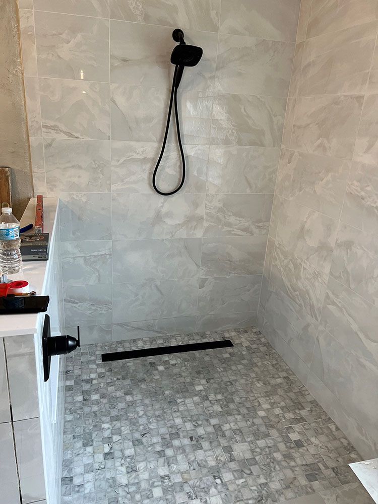 A bathroom with a walk in shower and a black shower head