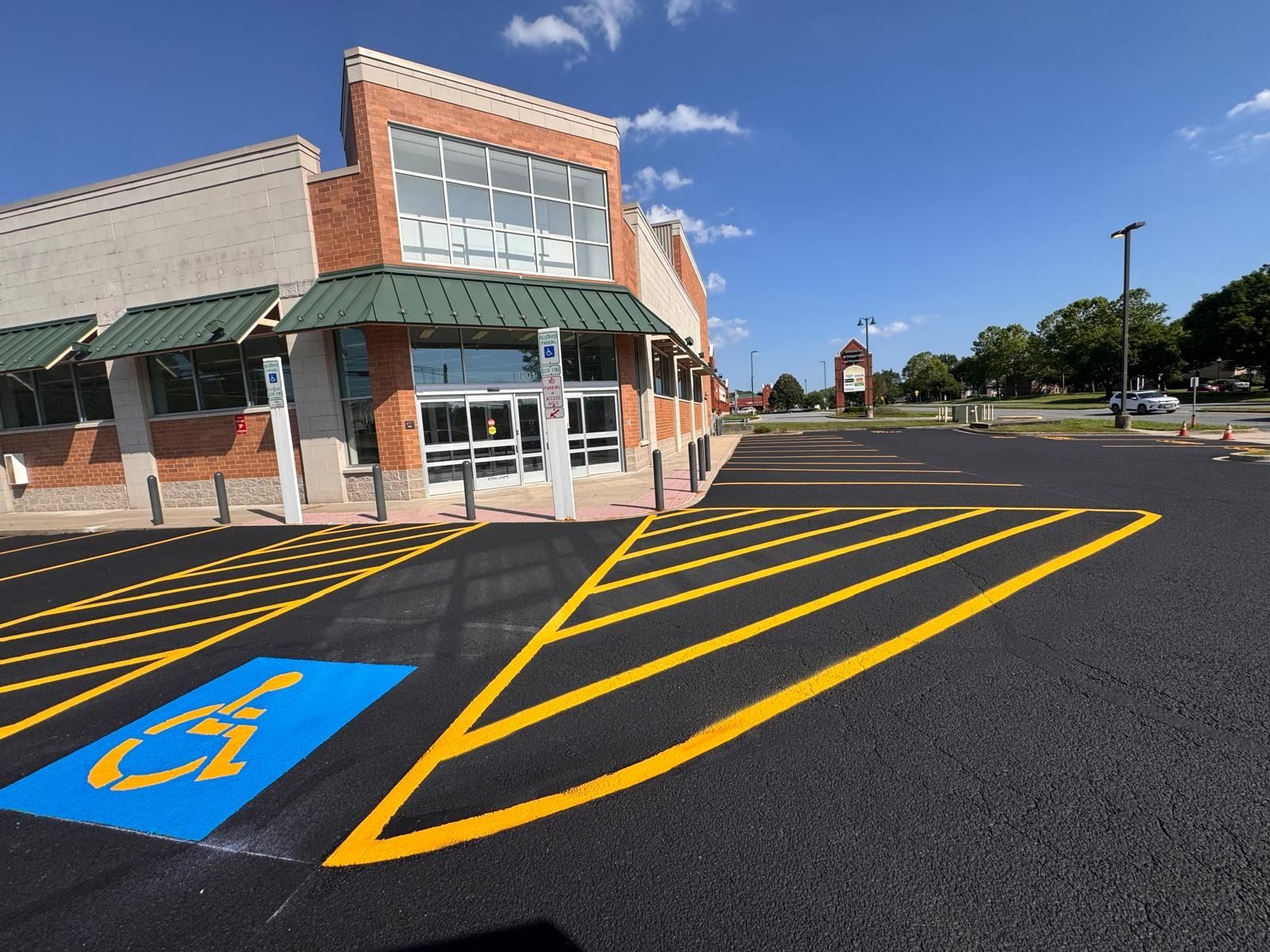 Accessible parking spaces and yellow striped no-parking zone outside a storefront on a sunny day