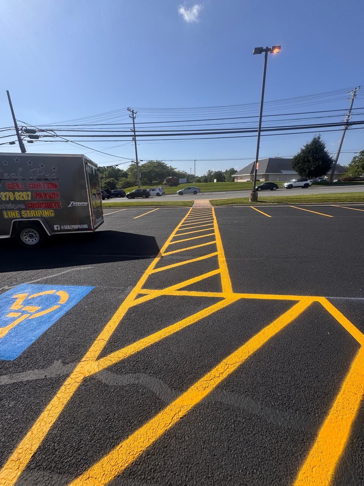 Yellow striped no-parking lane in a parking lot under a blue sky, with a utility truck at left.