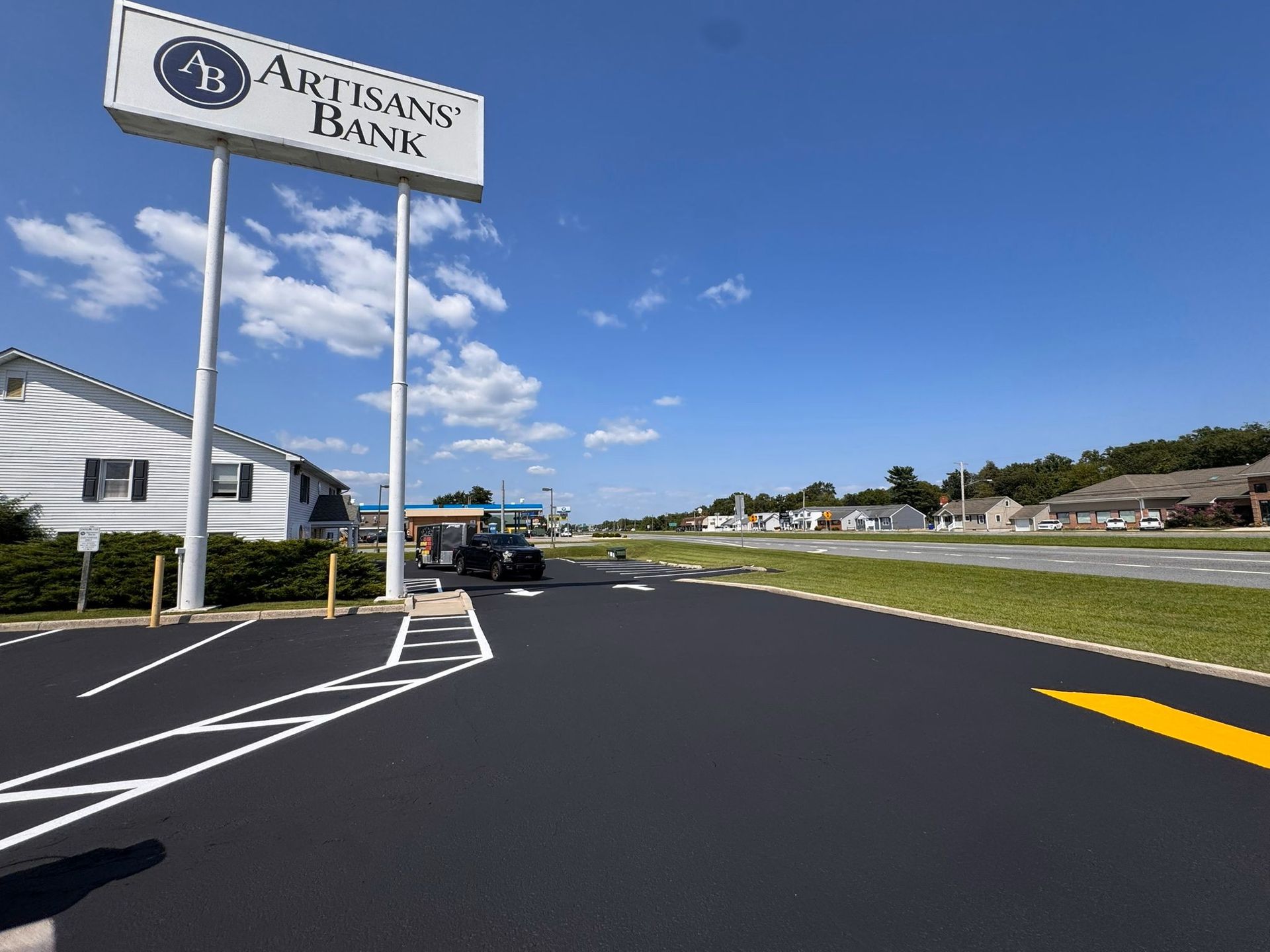 Auburn Bank sign beside a paved parking lot under a blue sky with scattered clouds.