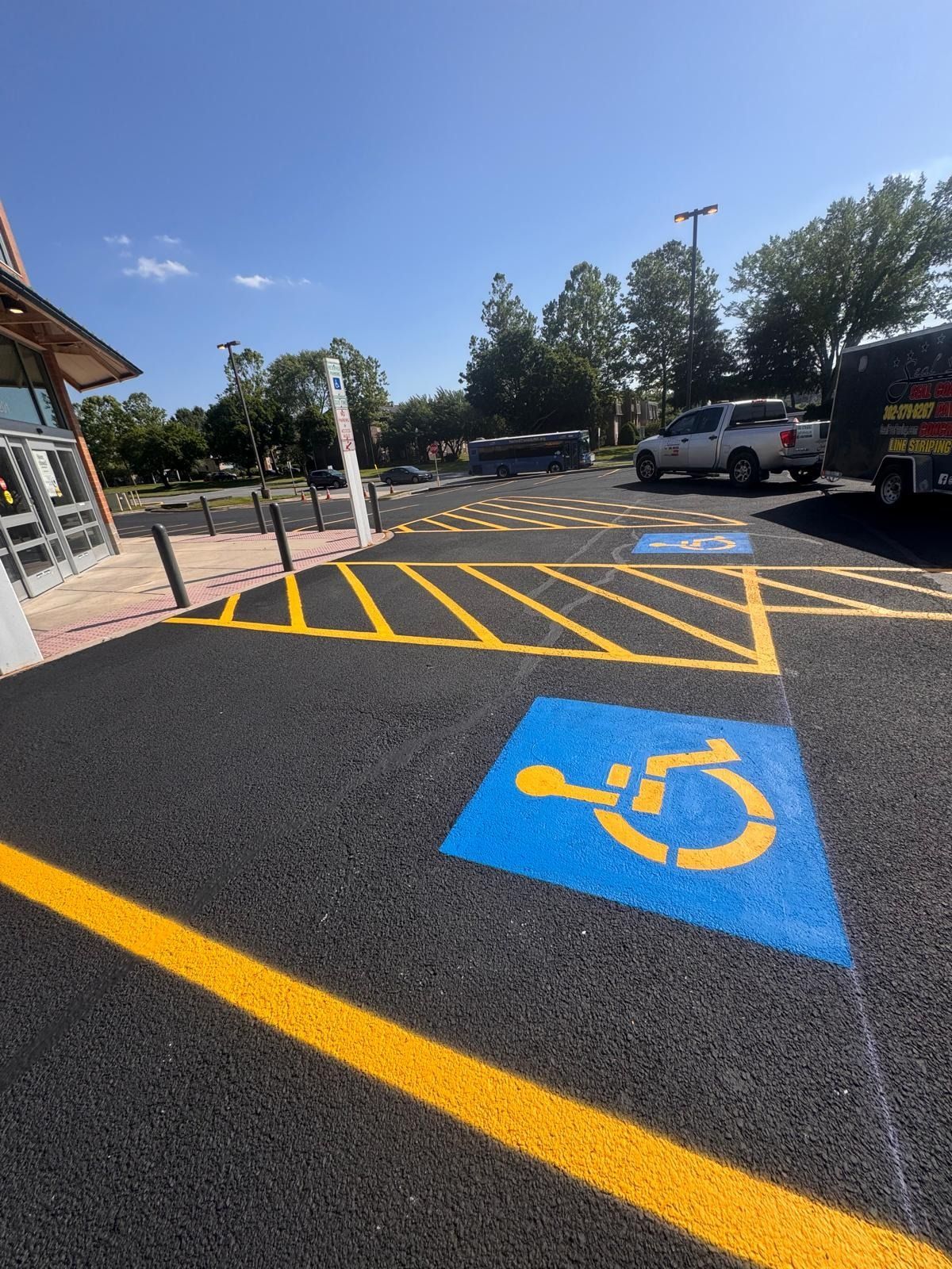 Accessible parking space with blue wheelchair symbol and yellow crosshatched no-parking zone in a lot
