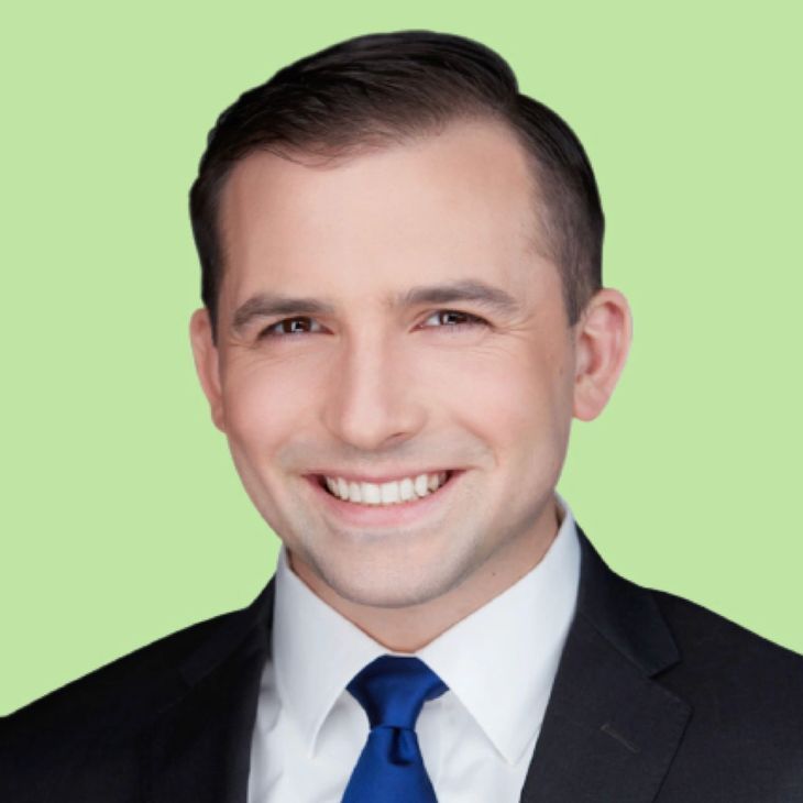 A man in a suit and tie is smiling for the camera