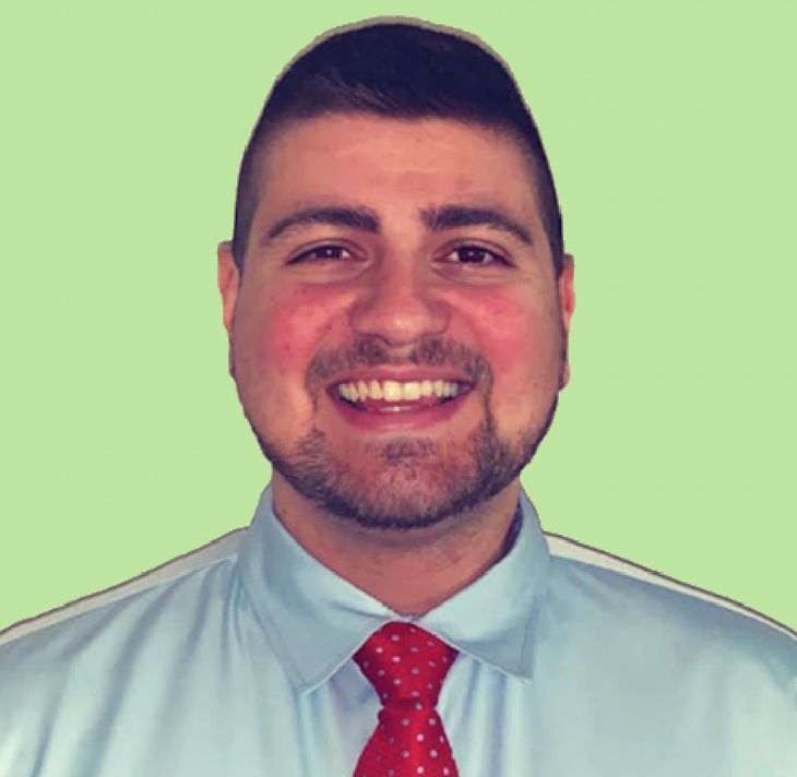 A man with a beard wearing a blue shirt and red tie