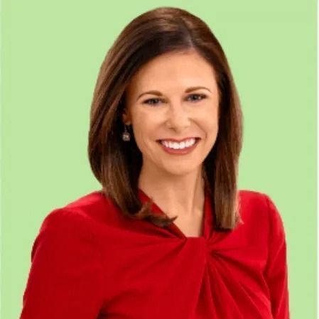 A woman in a red shirt is smiling and wearing earrings.
