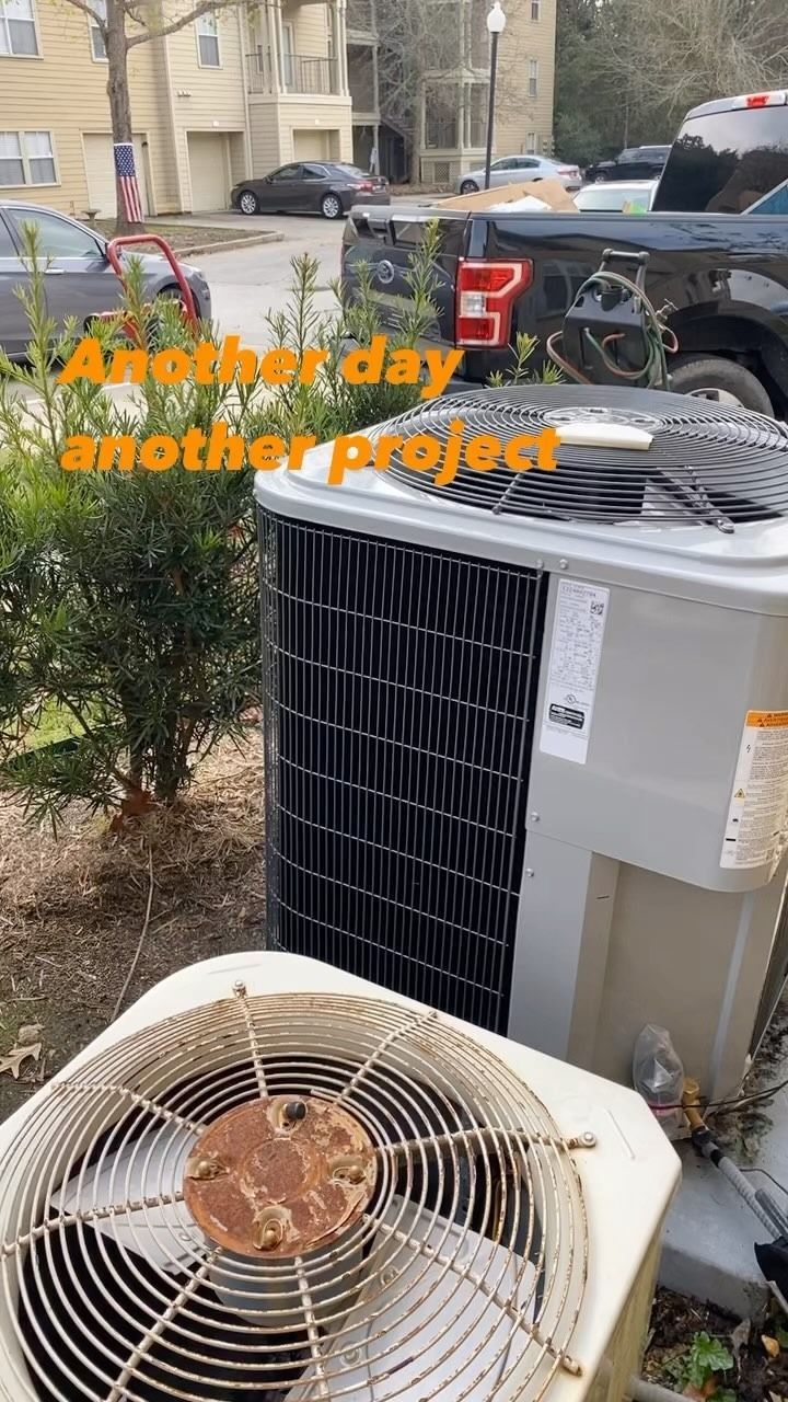 Two HVAC outdoor units sit side-by-side in a residential yard near a parked truck, with text reading 