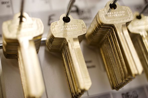 Stacks of gold-colored keys hanging on hooks, possibly in a hardware store.