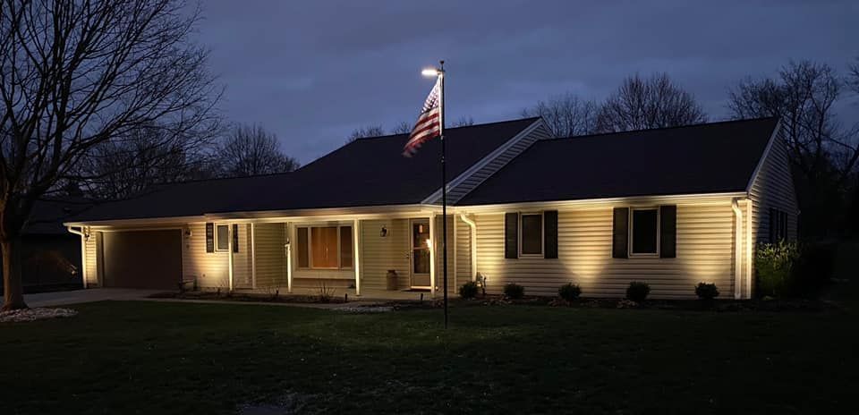 Single-story house at dusk, warmly lit with an American flag on a front pole.