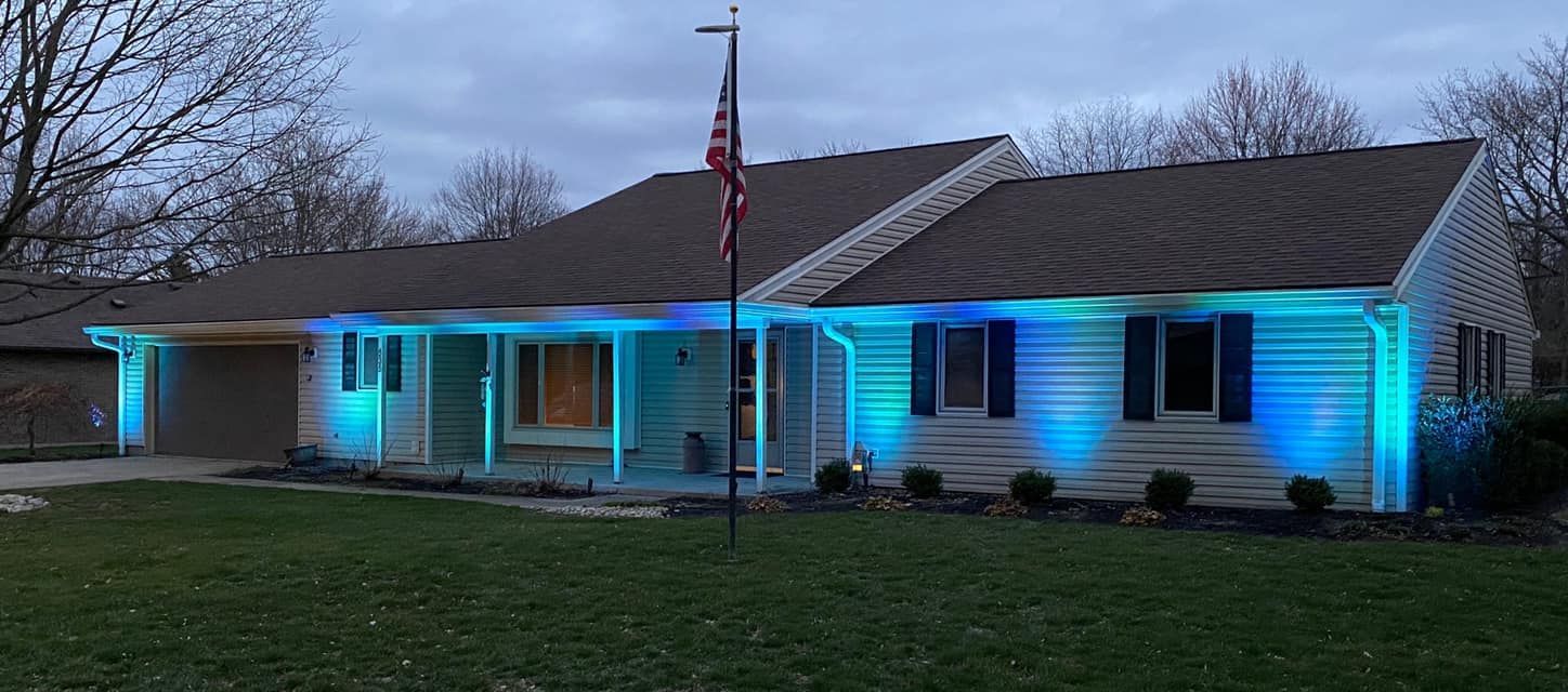 Single-story house at dusk with blue accent lights and an American flag in front yard.