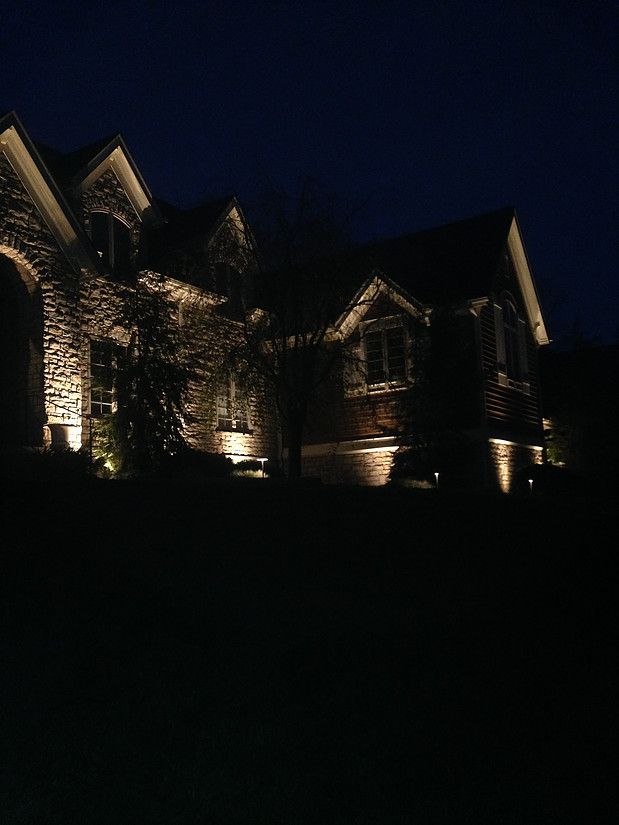 Dimly lit brick house at night with warm exterior lights against a dark sky
