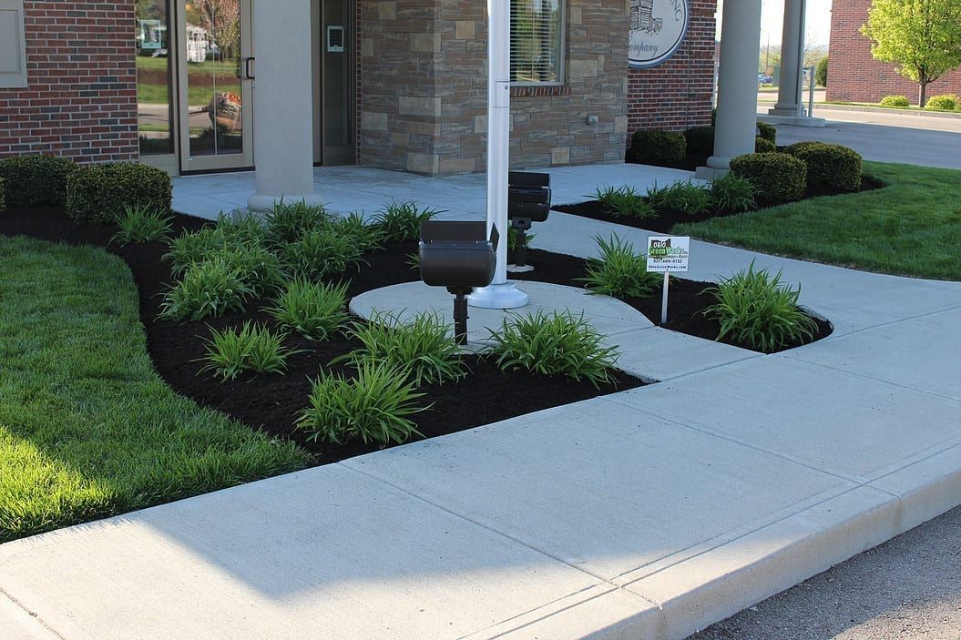 Front walkway and landscaped garden beds beside a brick house entrance