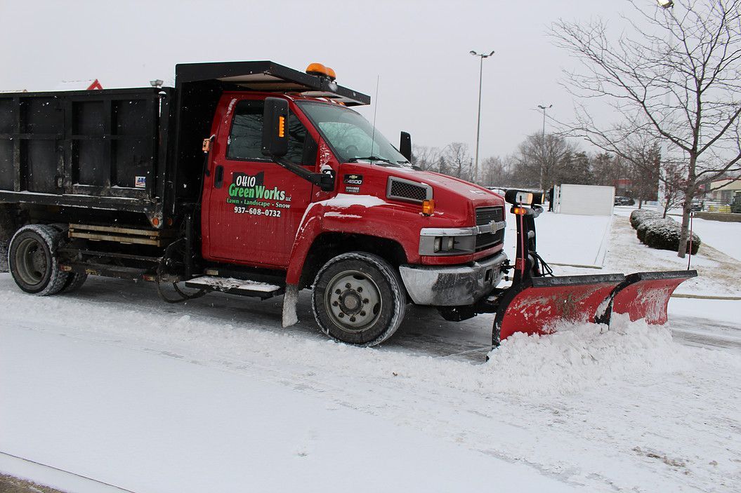 Red snowplow truck clearing a snowy road in winter