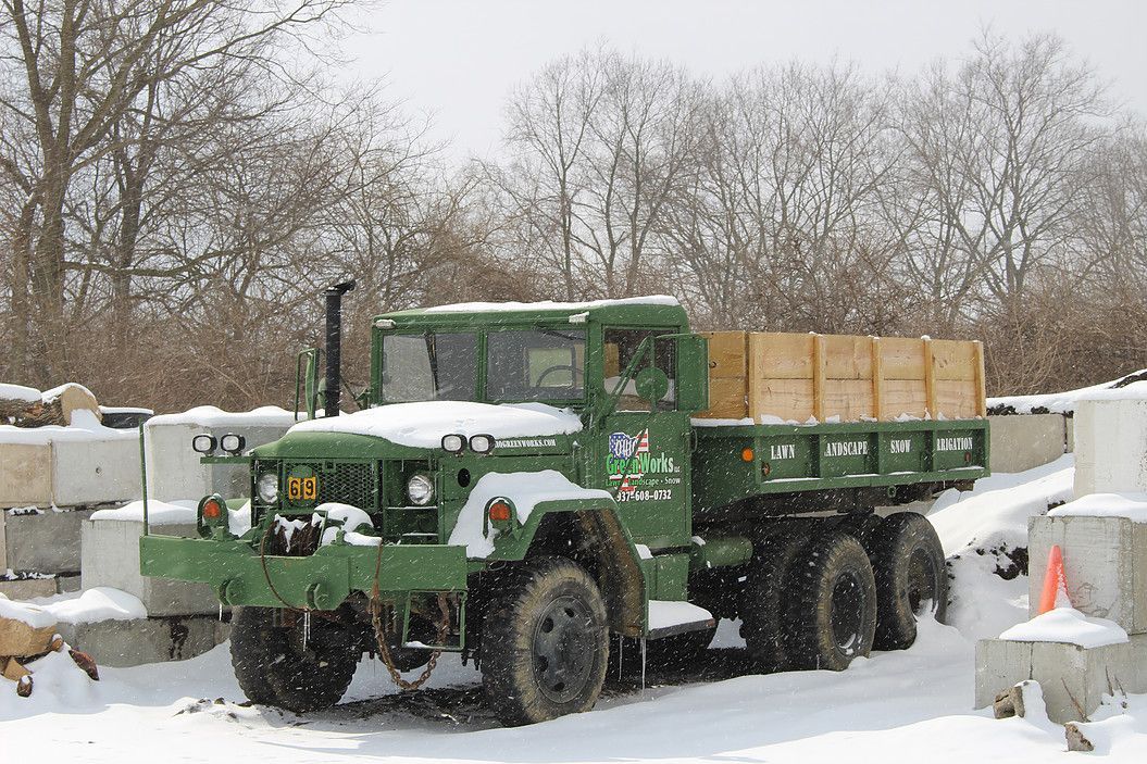 Green military truck loaded with crates in a snowy outdoor yard